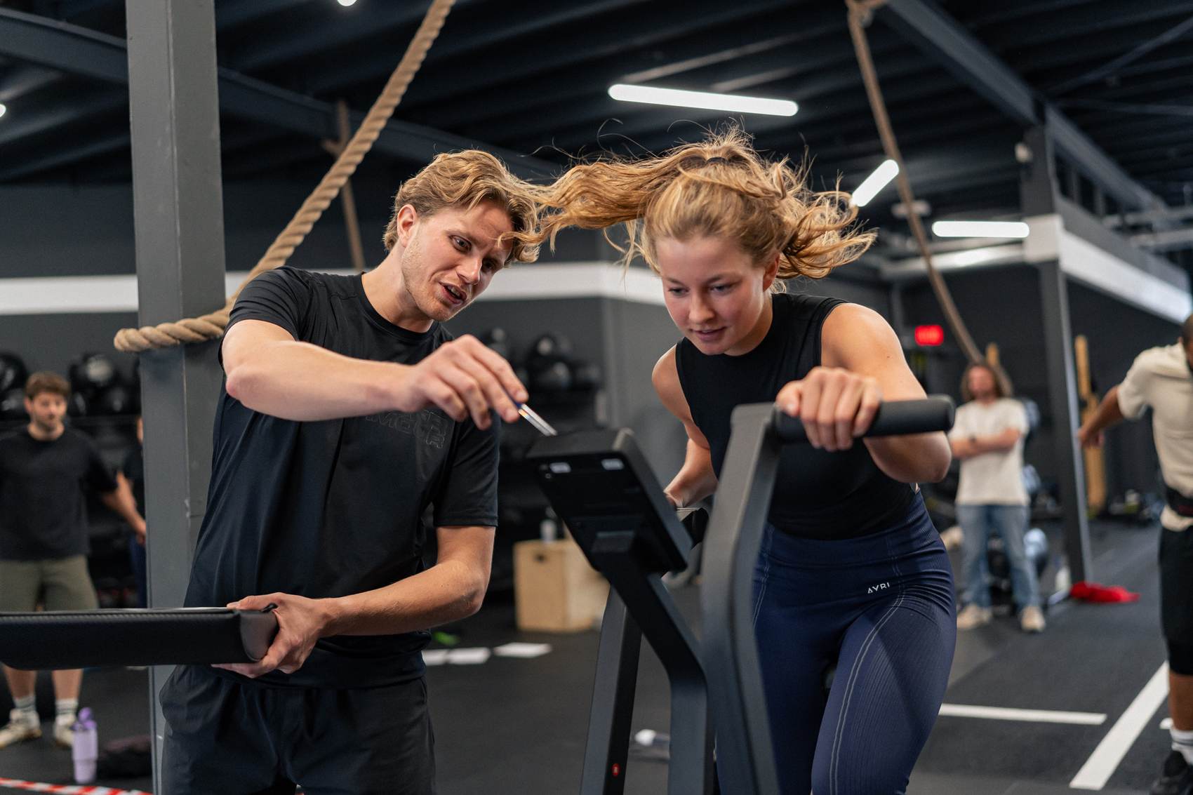Coach begeleidt een atleet op de airbike tijdens een Move-les.