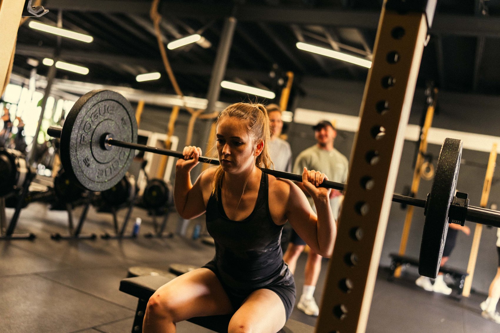 Atleet aan de squat, crew kijkt toe, tijdens een Build-les.